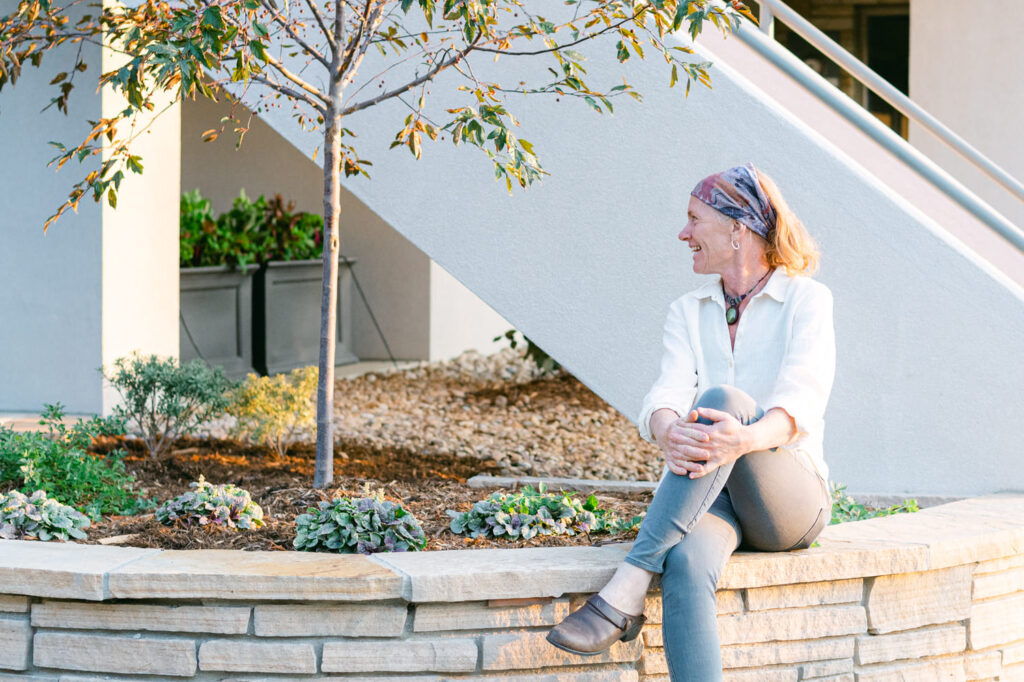 lady sitting on rock wall by flowers looking to the side