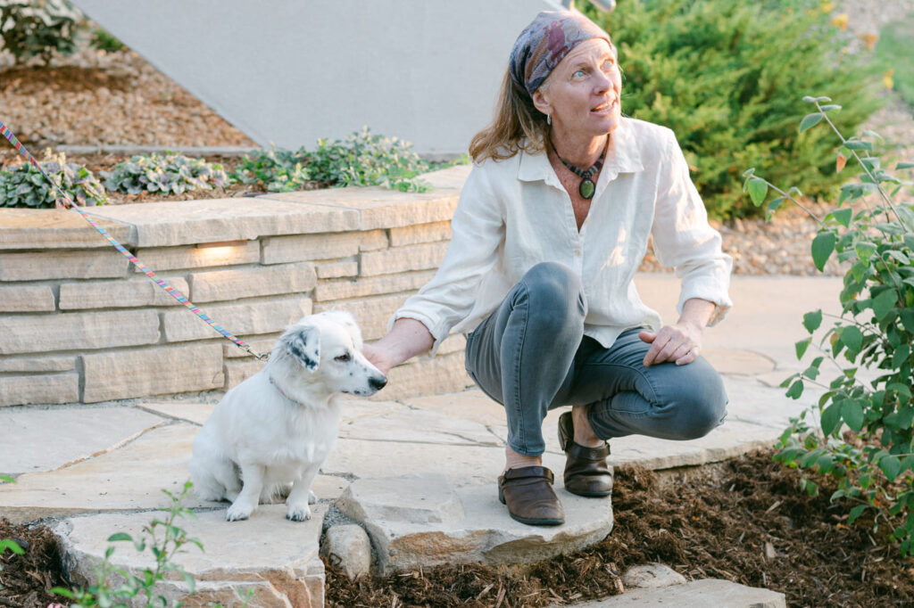 lady squatted down petting dog looking up in backyard