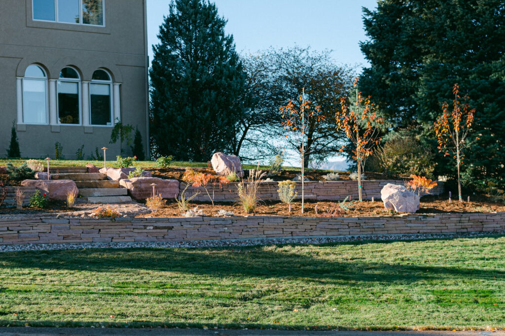 front yard landscaping with rock wall shrubs flowers and trees